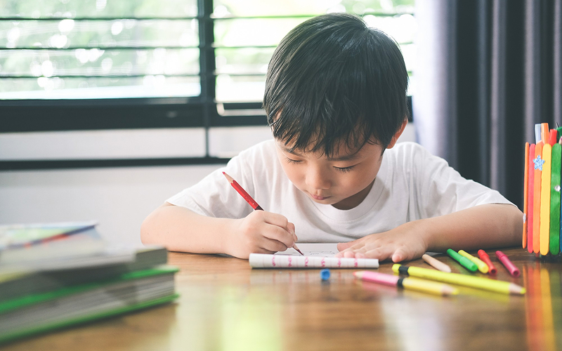 Young boy focused on learning activities at home.