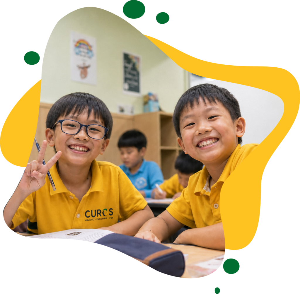 Two smiling schoolboys in CUROS uniforms pose at a classroom desk; one flashes a peace sign, with classmates working behind them.